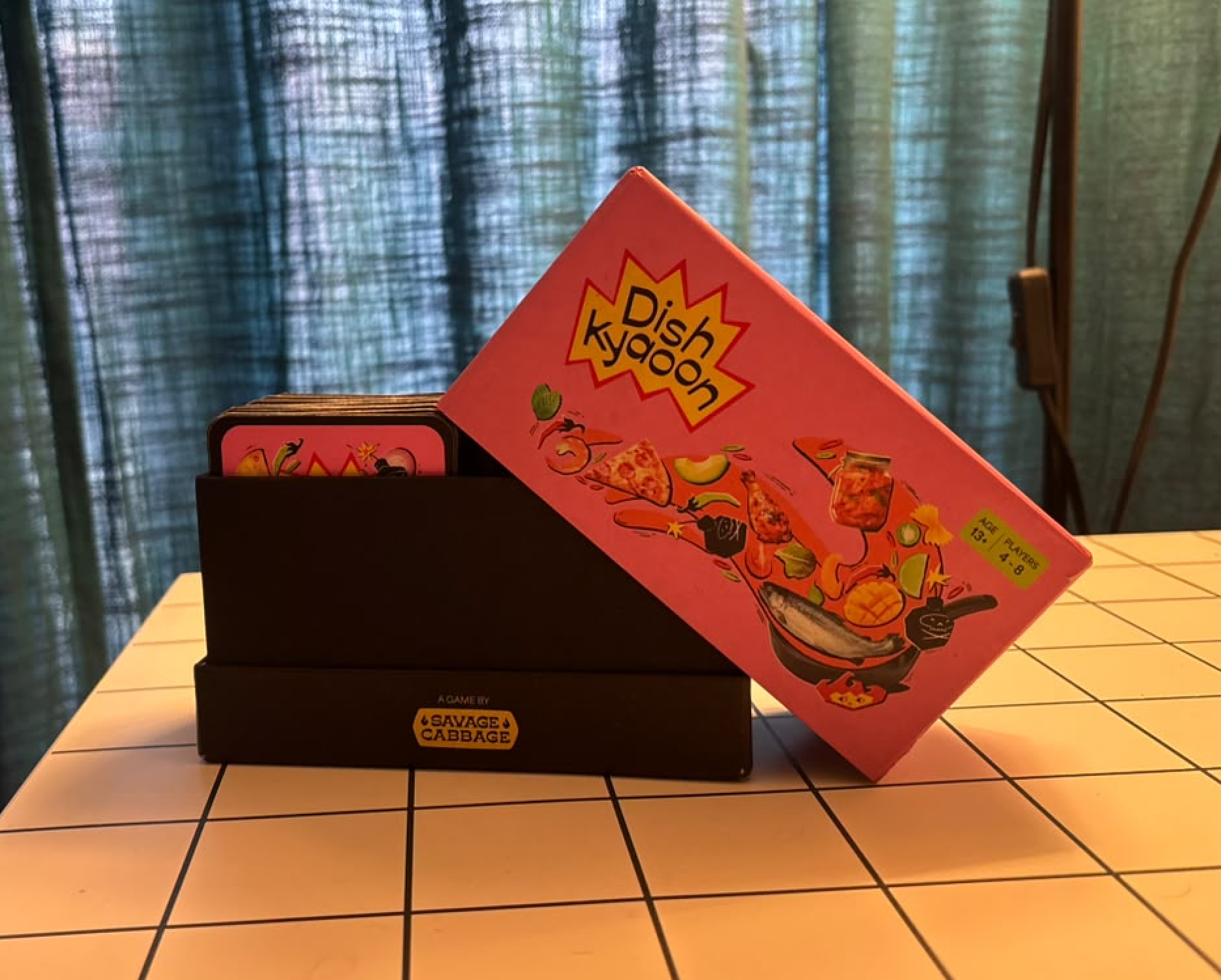 The finished Dish Kyaoon box with its pink illustrated lid resting against the open card box.